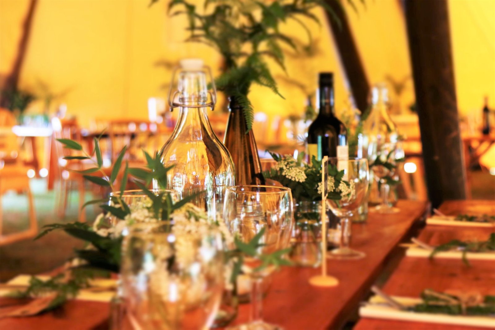 Beautifully arranged dining table with greenery and glassware in a warm indoor setting.