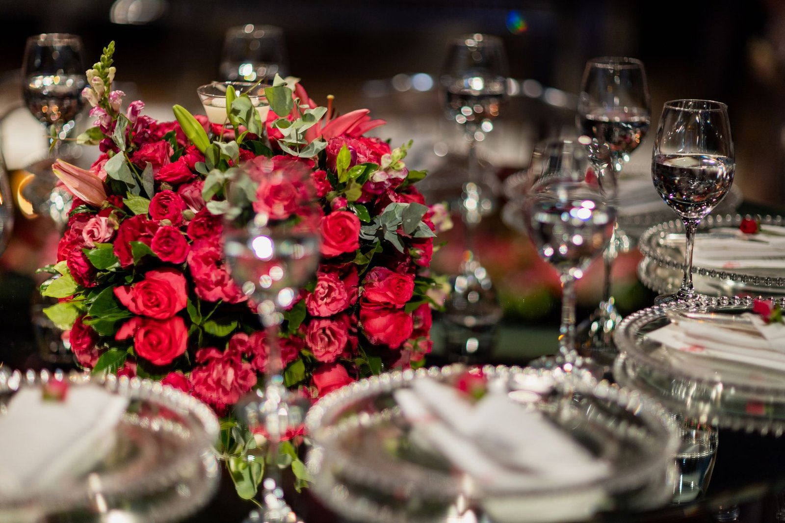 A beautiful table setting featuring red roses and crystal glassware for a sophisticated event.