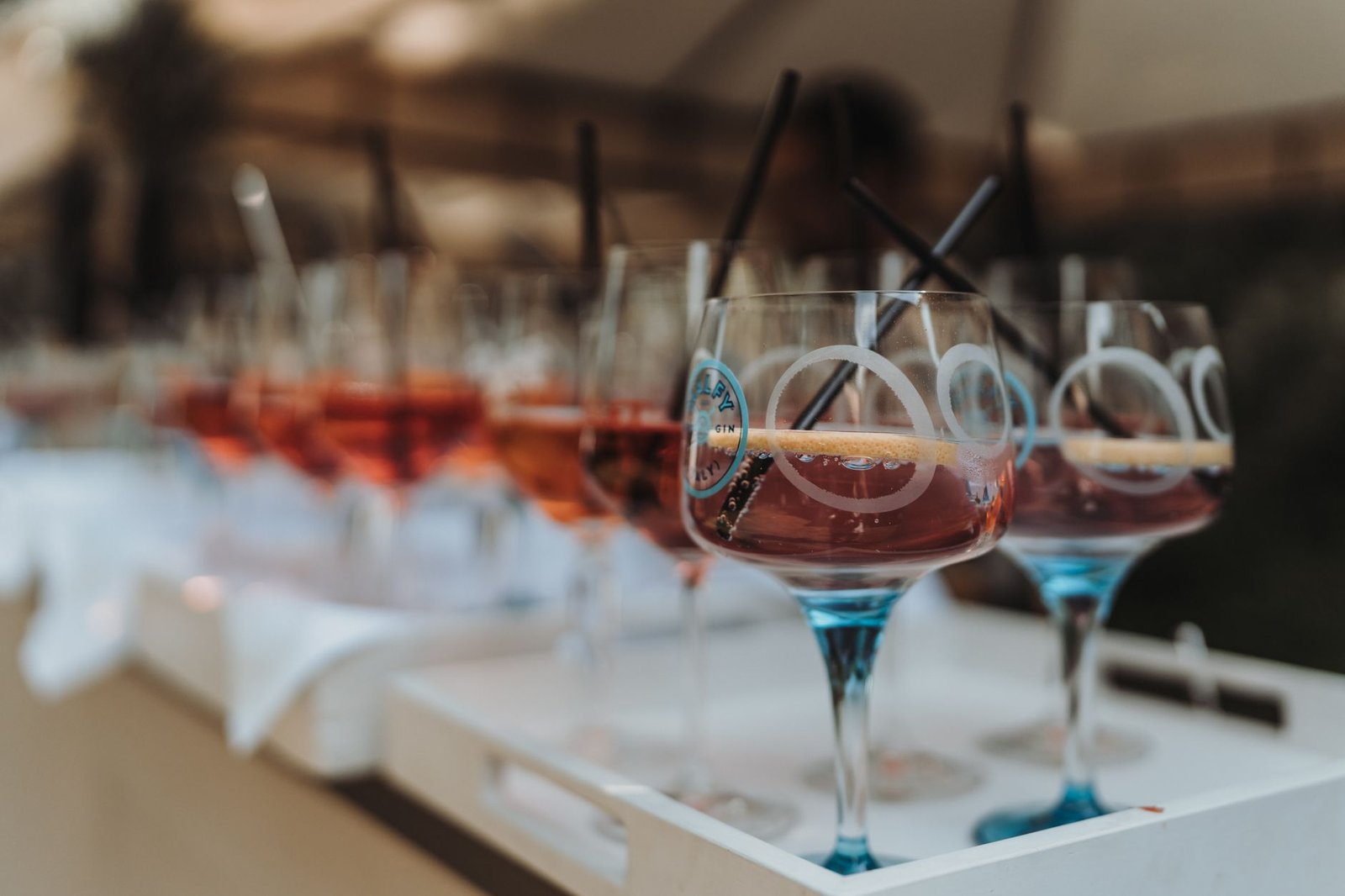 Close-up of elegant cocktails in glasses with straws on a tray, ideal for banquets and events.