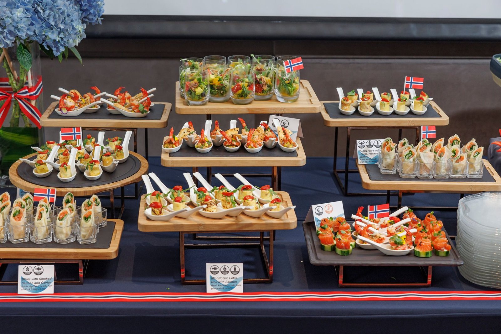 A variety of Nordic dishes beautifully arranged with Norwegian flags on a buffet table.