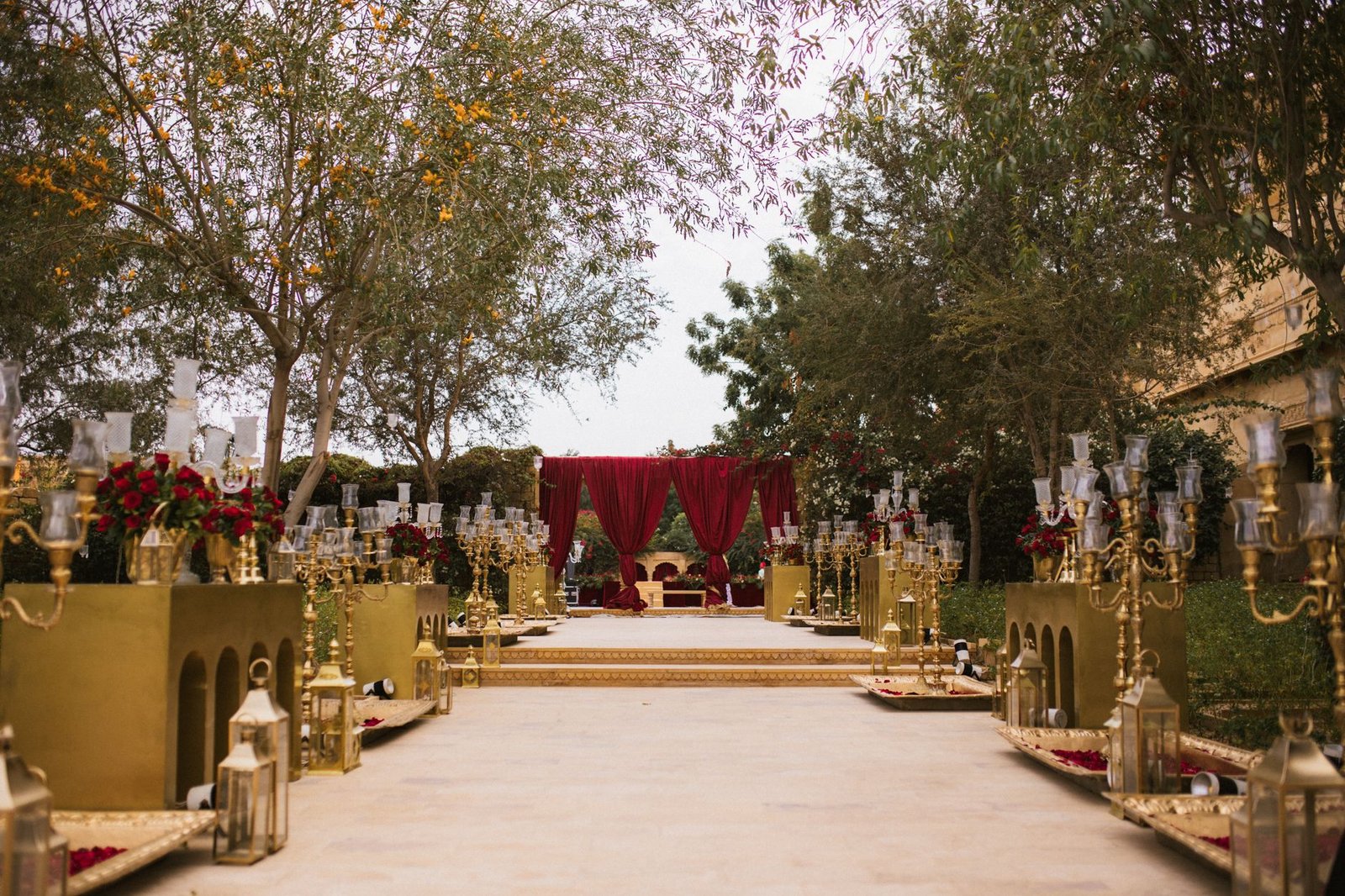 Luxurious outdoor wedding setup with ornate gold decor and floral arrangements.