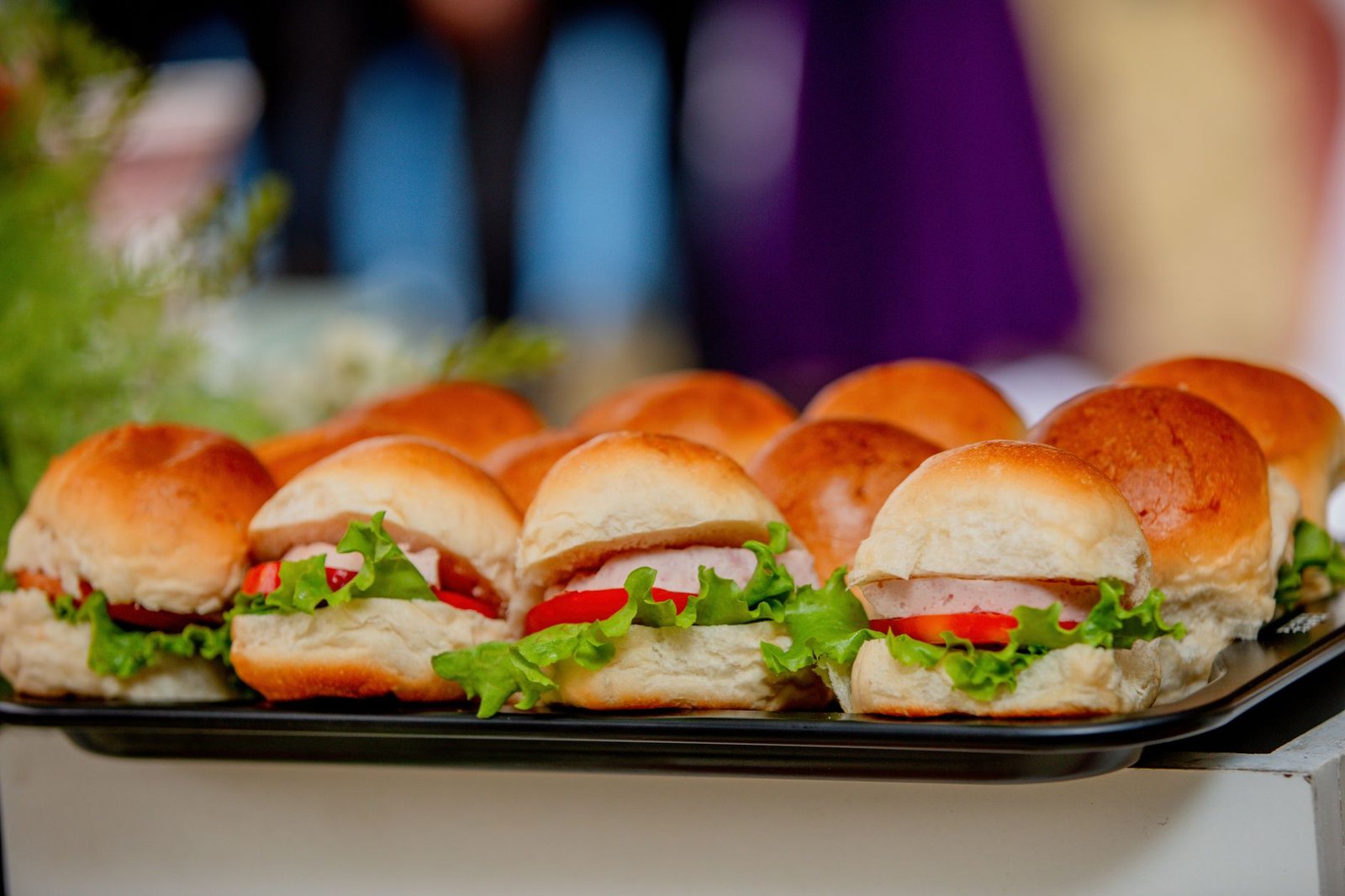 Tampilan dekat piring berisi sandwich mini segar berisi selada, tomat, dan roti.