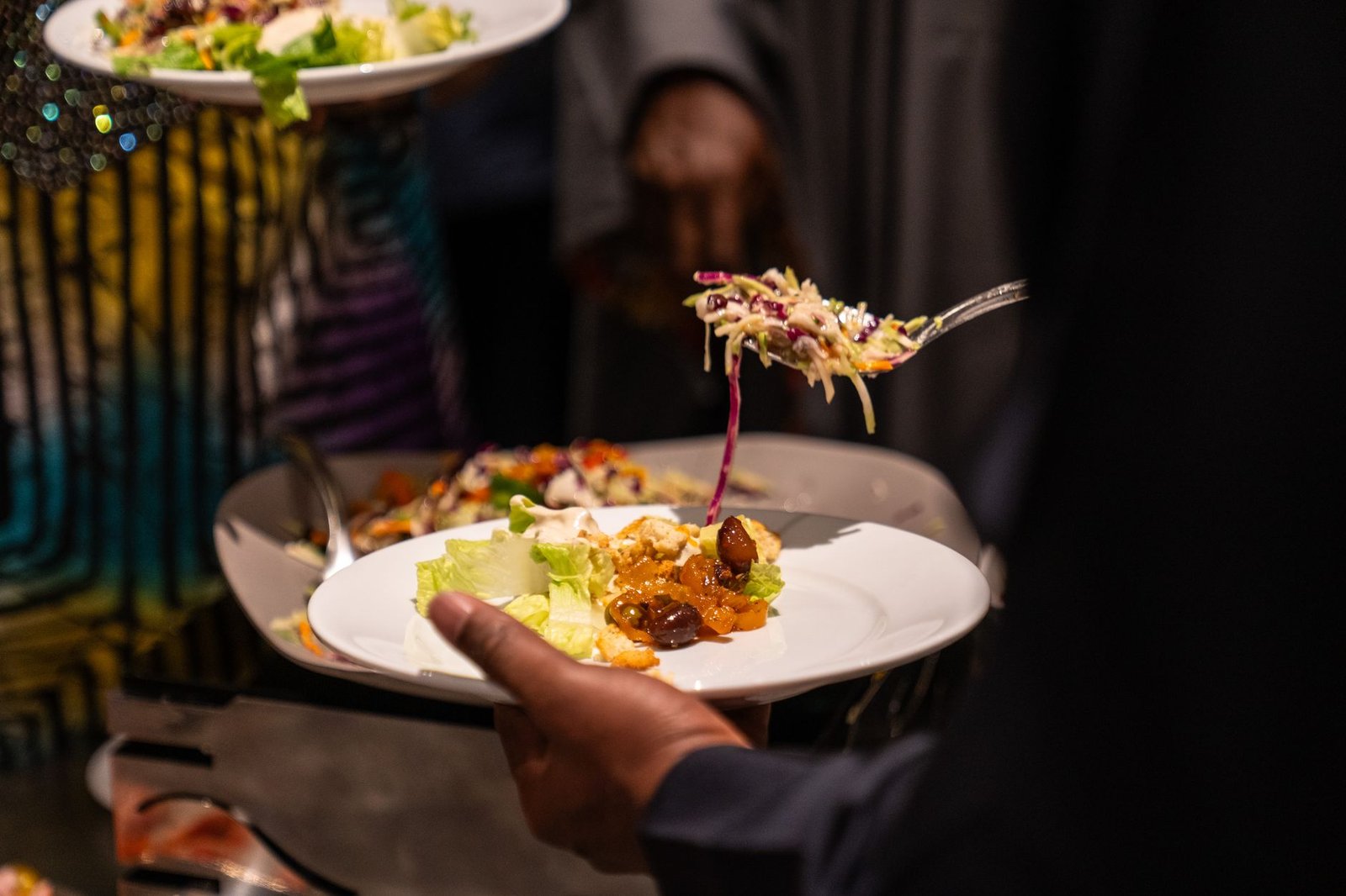 A close-up view of guests serving themselves diverse dishes at a buffet, highlighting culinary diversity.