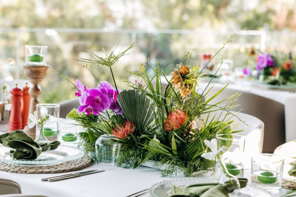 Beautifully arranged floral centerpiece with orchids on an outdoor event table.