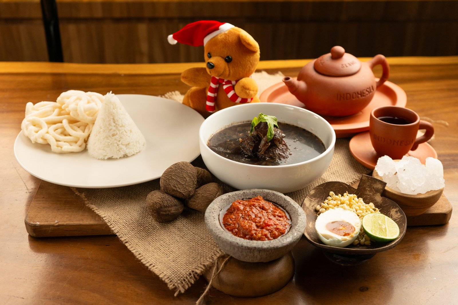 Delicious traditional Indonesian cuisine arrangement featuring rice, sambal, and herbal teapot.