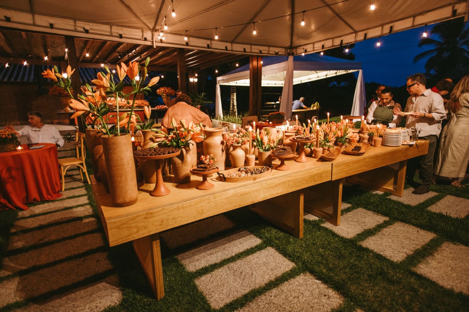 A beautifully decorated outdoor wedding setup at night, featuring terracotta decor and ambient lighting.