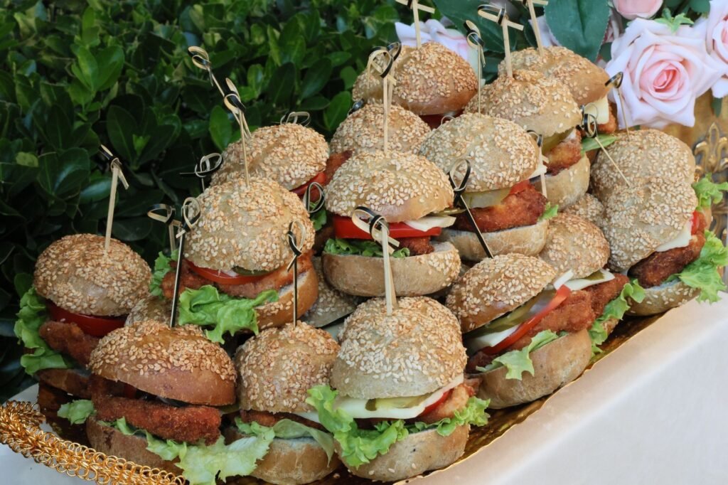 Burger ayam mini yang lezat dengan selada, tomat, dan roti wijen, ideal untuk acara-acara.