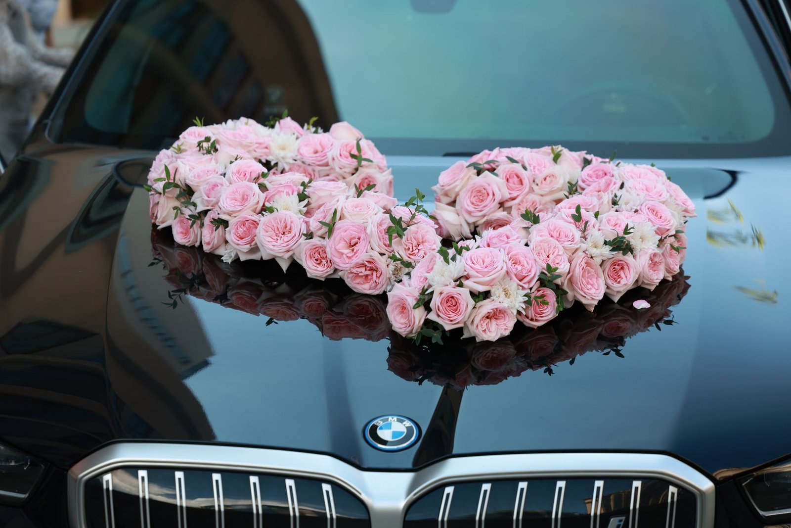 A luxurious car adorned with a beautiful heart-shaped arrangement of pink roses, perfect for weddings.