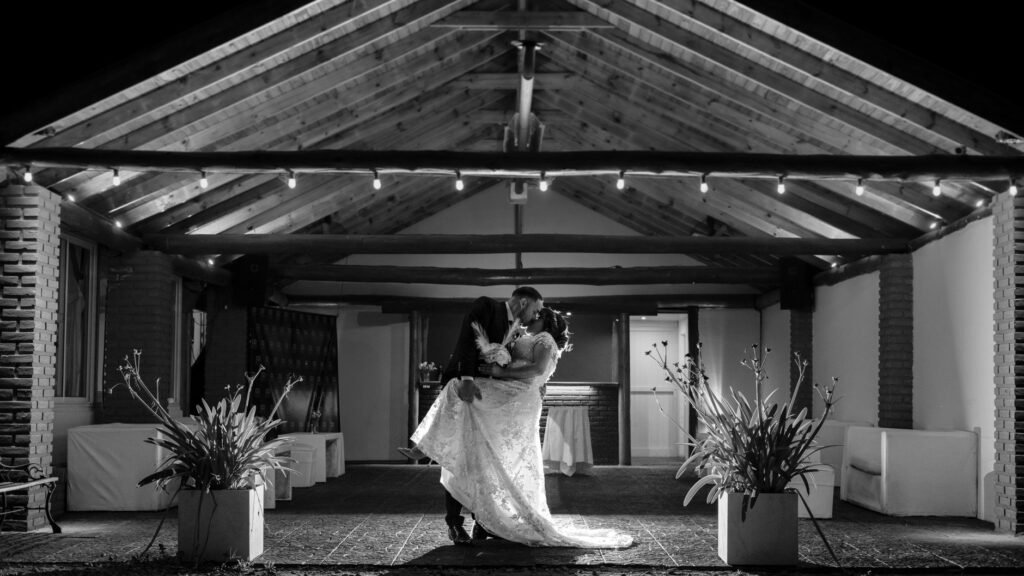 A romantic black and white image of a couple embracing in a serene wedding setting.