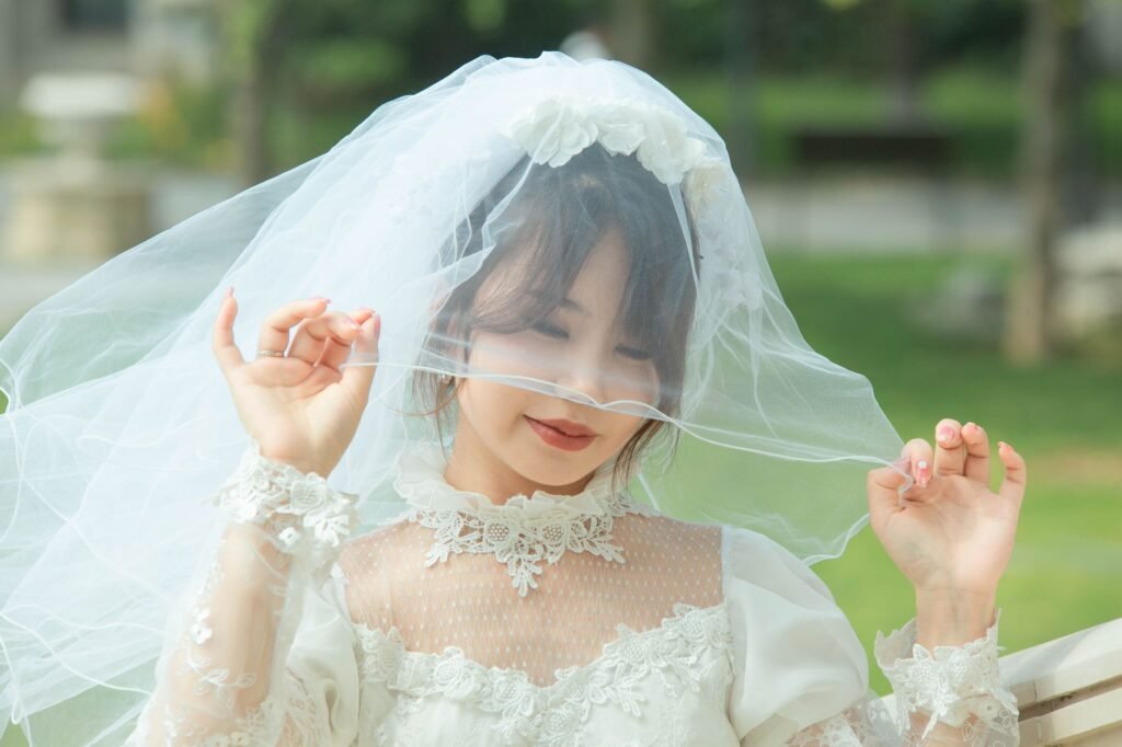 Pengantin cantik di luar ruangan dengan gaun pengantin renda dan penutup kepala, memancarkan keanggunan.