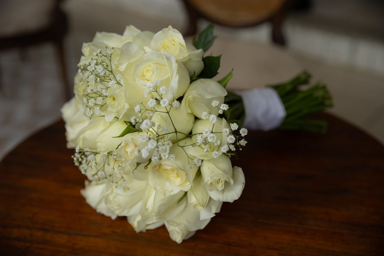 Buket mawar putih yang indah tersusun elegan di atas meja kayu.