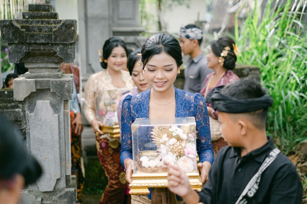 Masyarakat Bali mengenakan pakaian adat berpartisipasi dalam perayaan adat, sambil membawa nampan hadiah berhias.