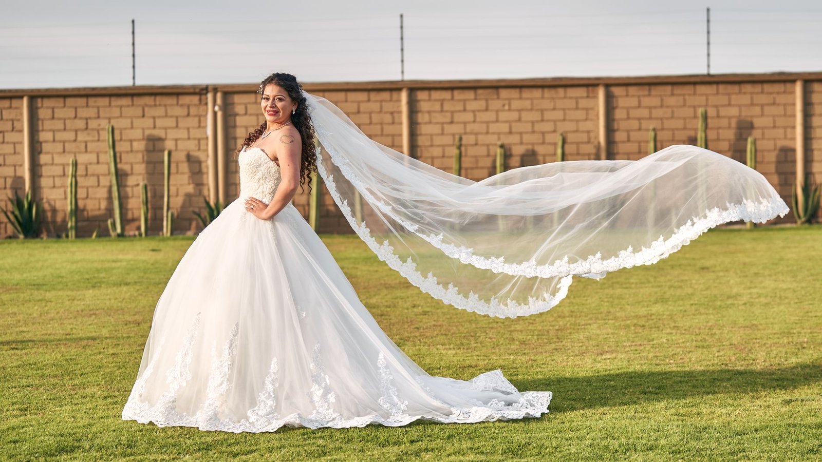 Pengantin cantik berpose dalam gaun berkibar di luar ruangan, memancarkan keanggunan dan kegembiraan.