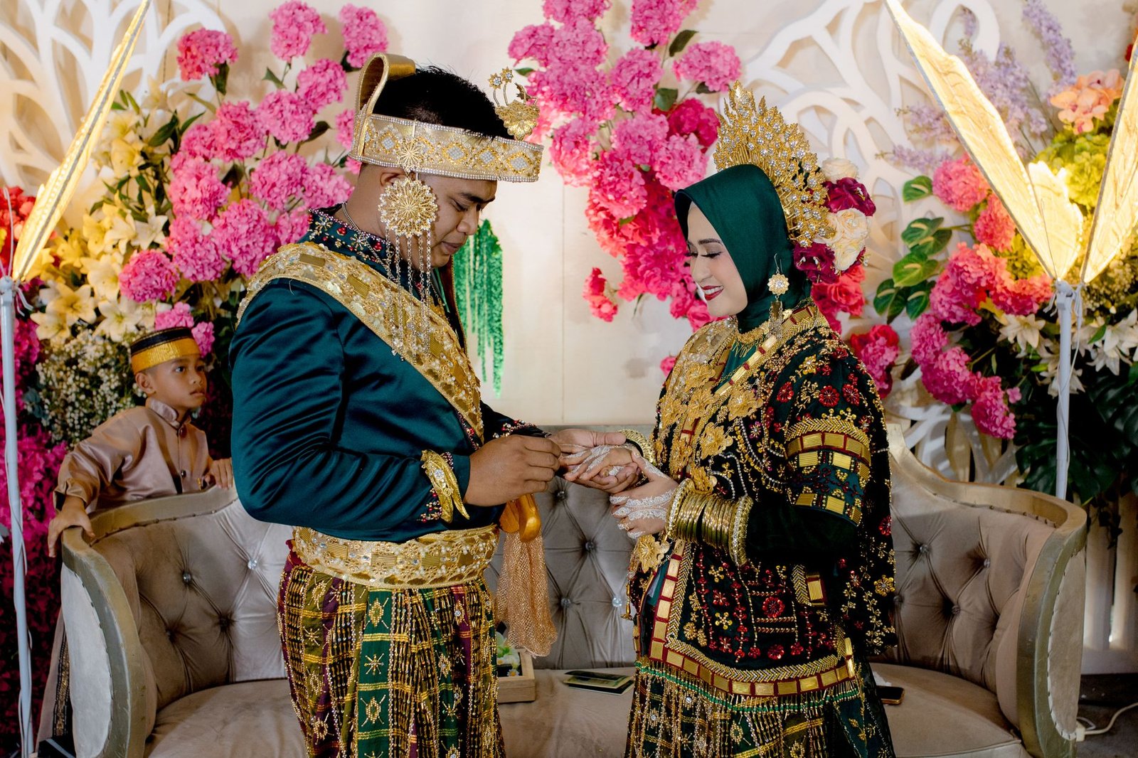 Pasangan bertukar cincin dalam upacara pernikahan tradisional yang meriah di Kendari, Indonesia.