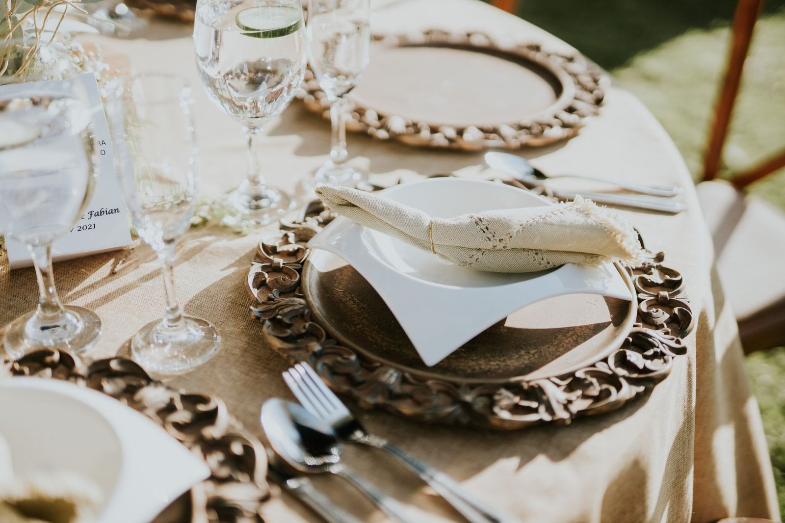 Close-up of a beautifully set wedding table with plates and cutlery in natural light.