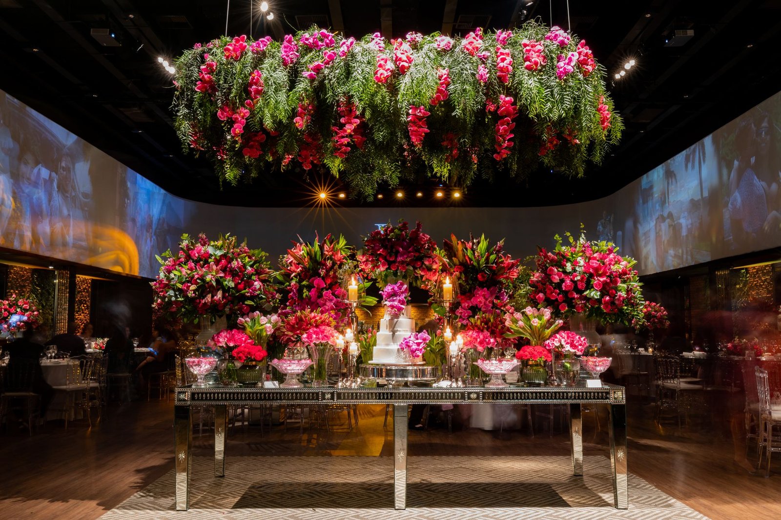 Stunning flower arrangements and cake table set in an elegant indoor venue.