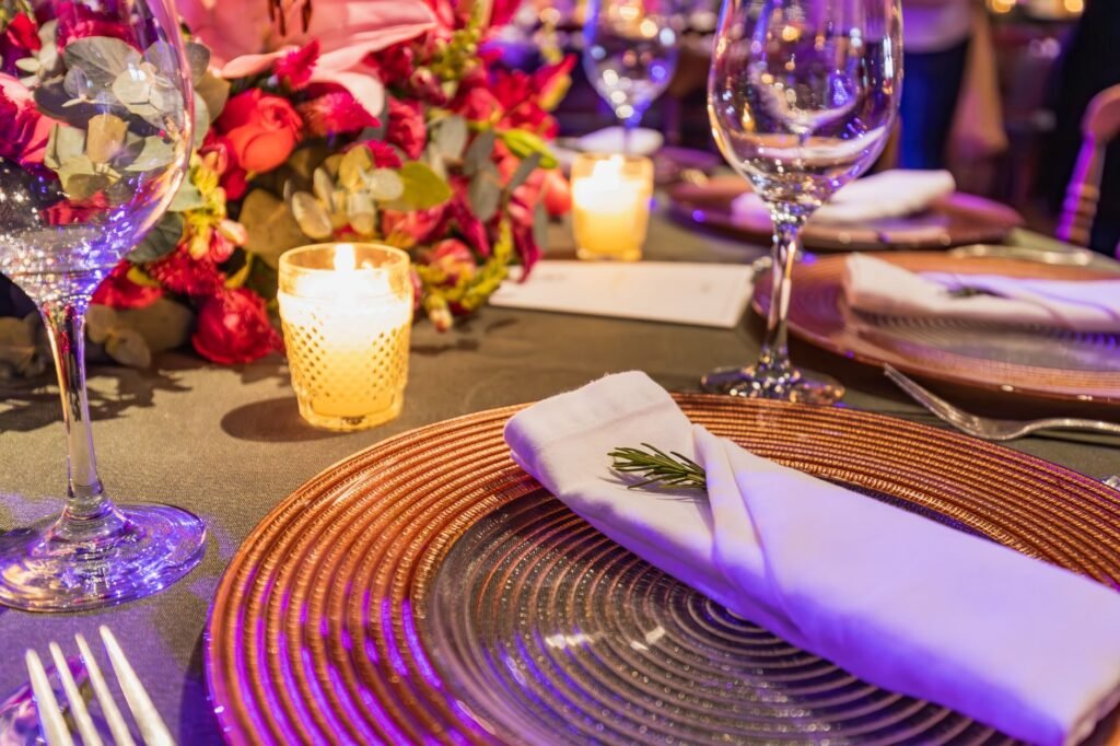 Close-up of a chic table setting with flowers, glassware, and candlelight ambiance.