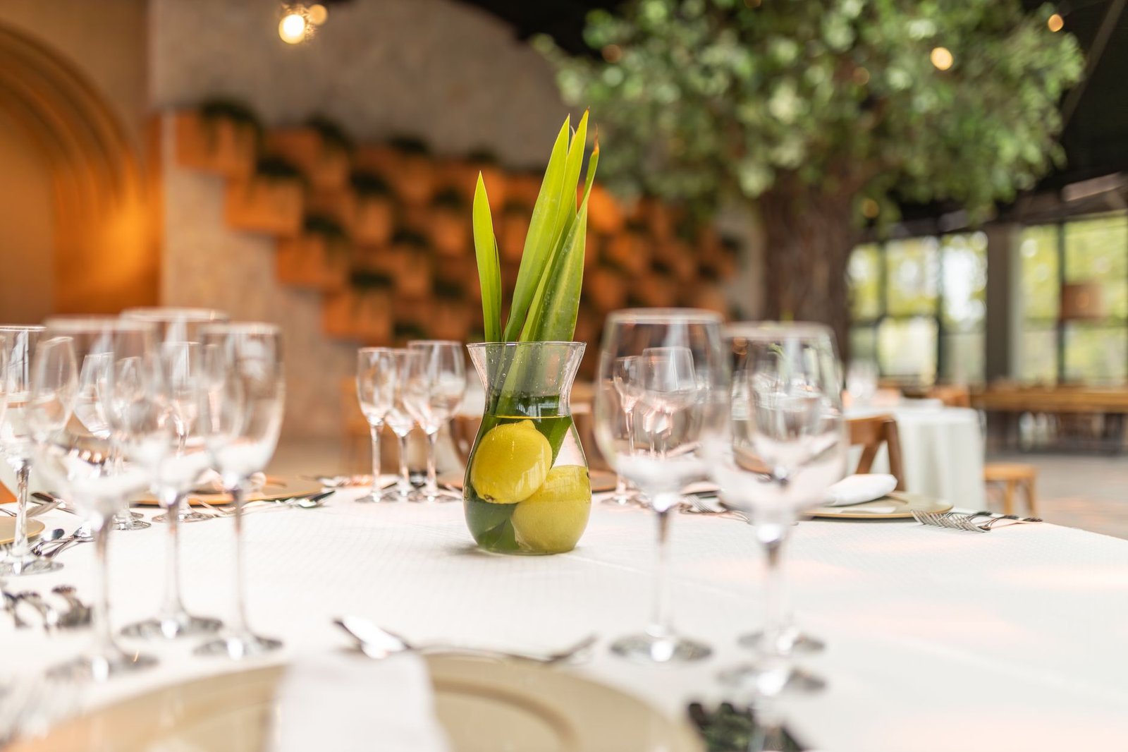 A beautifully decorated table in a restaurant, featuring lemons and a glass vase centerpiece.