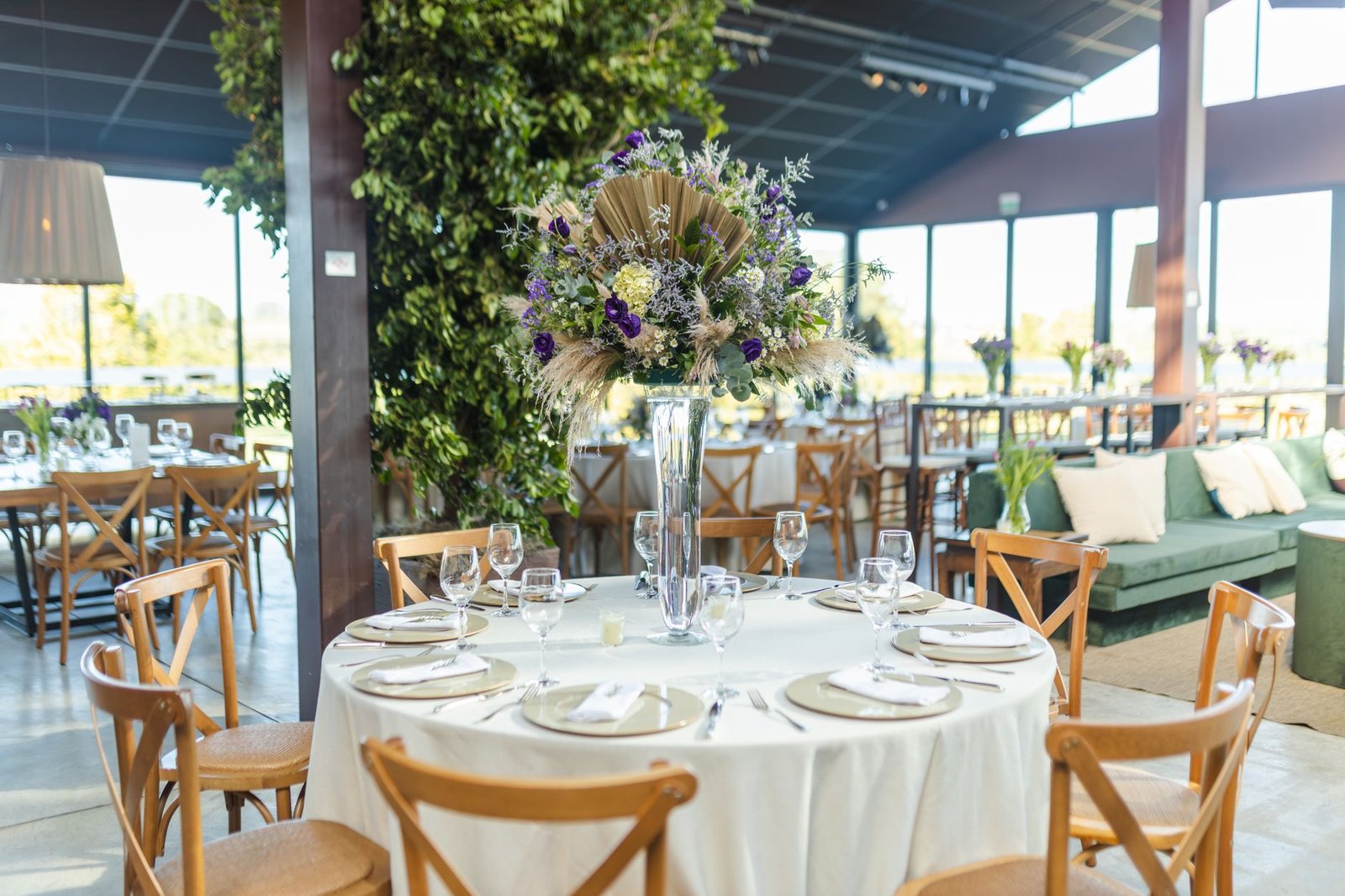 Beautiful rustic wedding table setting indoors with floral centerpiece and large windows.