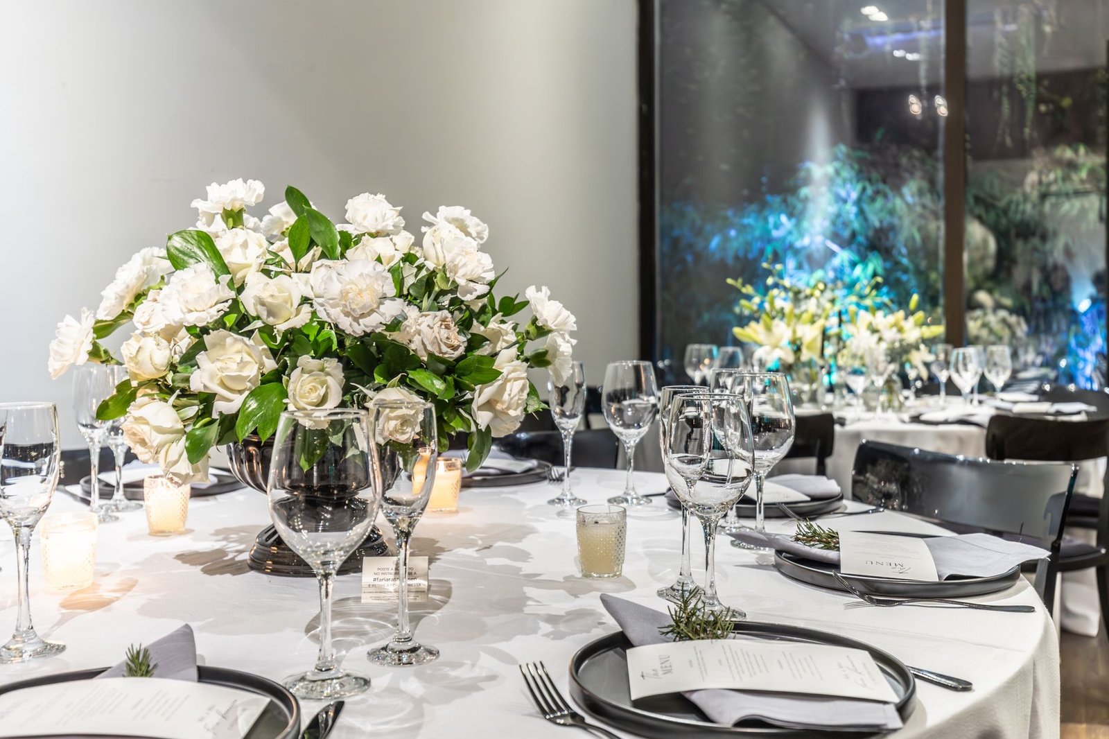 Beautifully arranged wedding table with white floral centerpiece, glassware, and candles.
