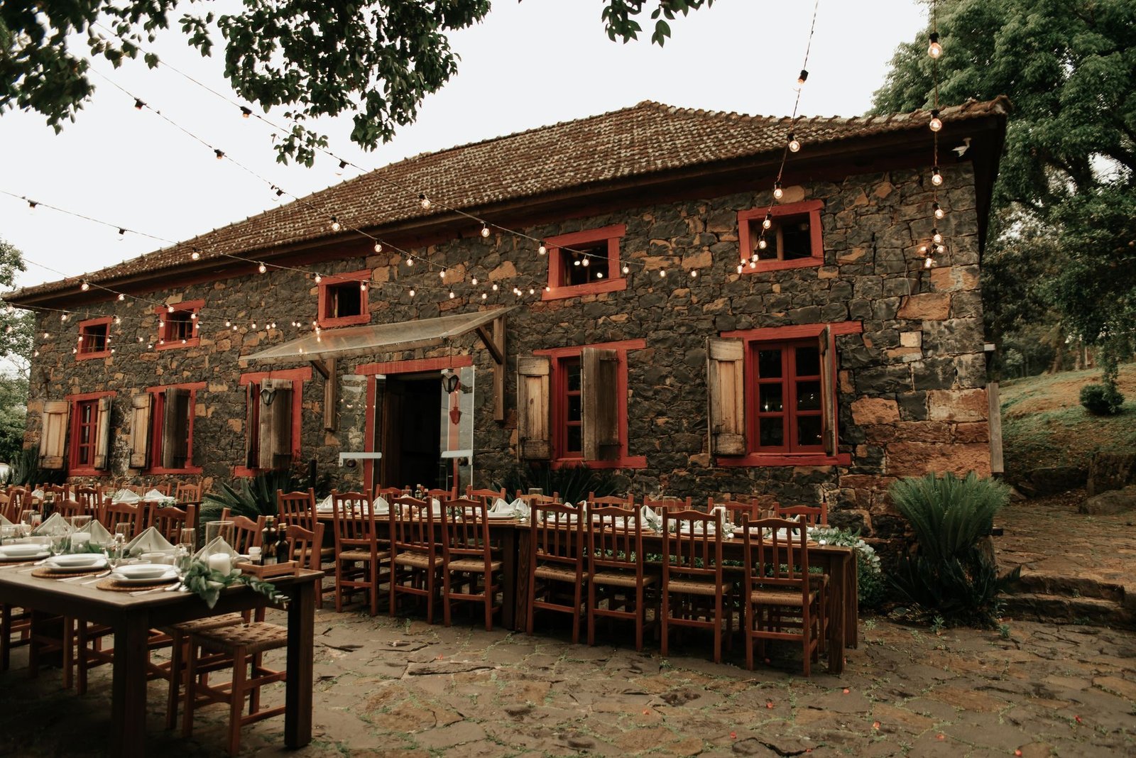 Charming stone building with outdoor dining setup under string lights.