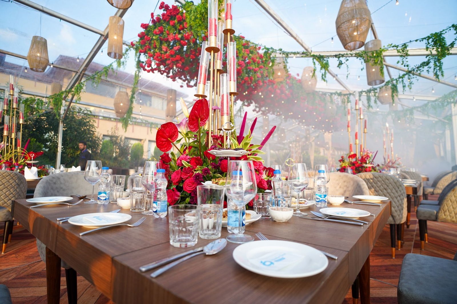 Exquisite dining setup in a glass pavilion with vibrant floral arrangements and elegant tableware in Srinagar.