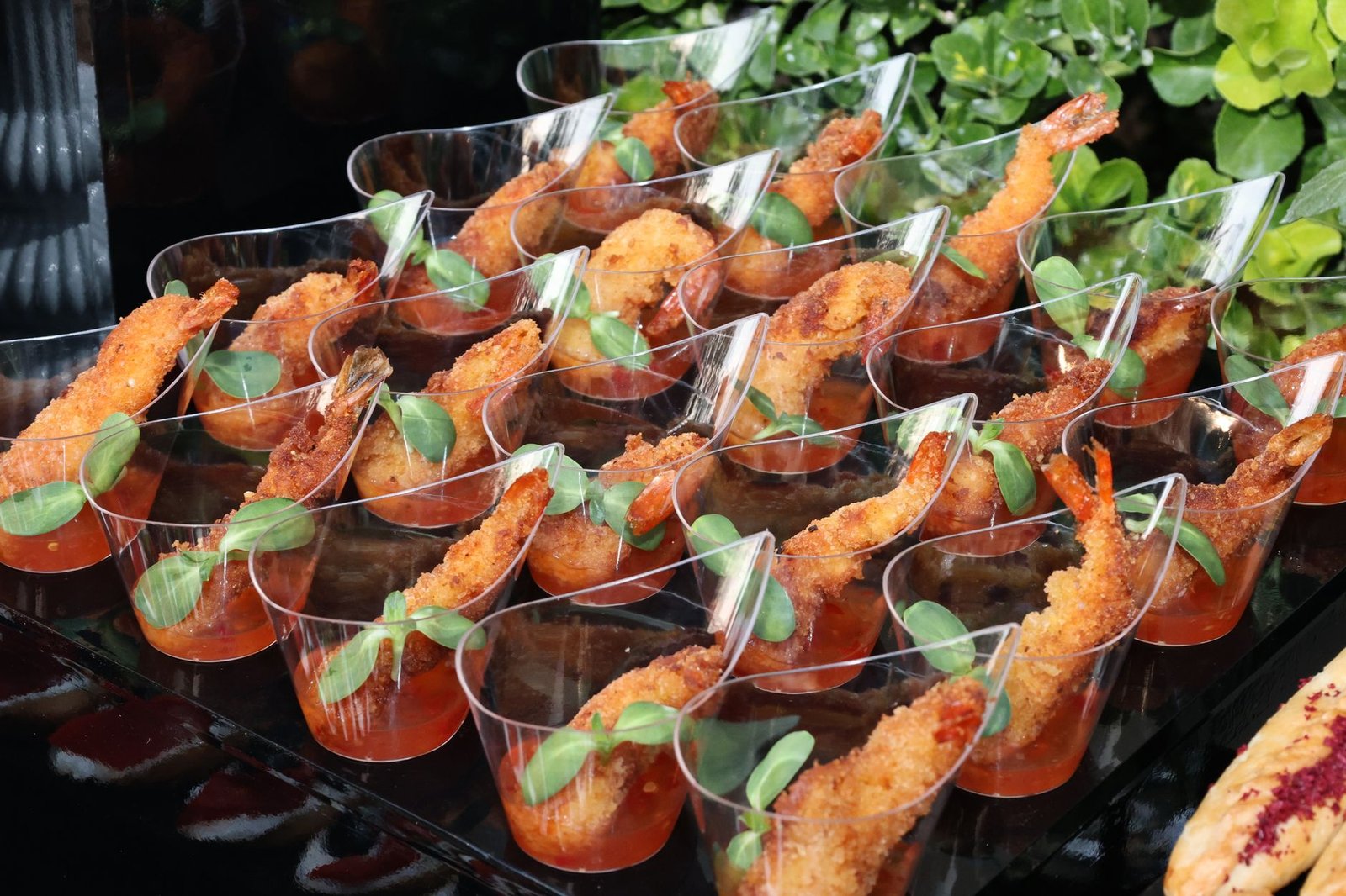 Appetizing breaded shrimp served in cocktail glasses with sauce and greens, perfect for catering events.