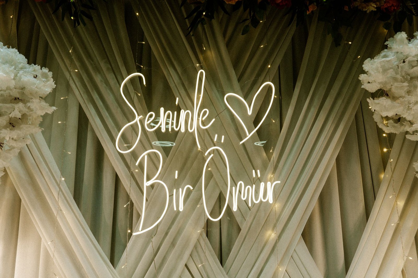 A romantic backdrop featuring a neon sign that reads 'Seninle Bir Ömür' in an elegant setting.