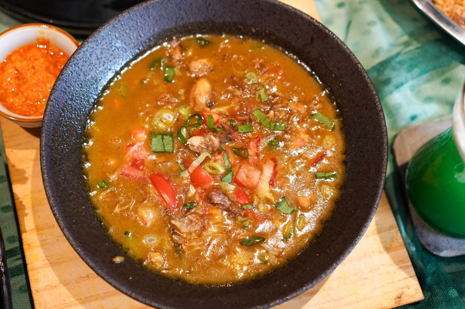 Delicious Indonesian Sop Buntut served with spicy sambal on a wooden table.