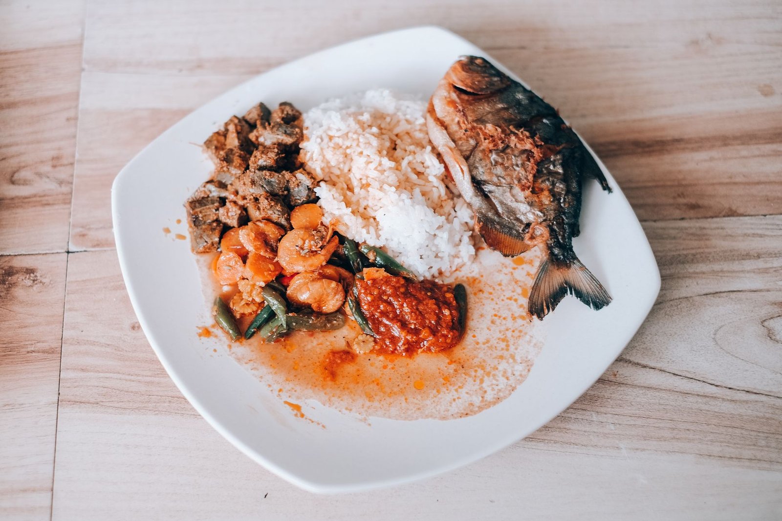 An appetizing plate featuring Indonesian cuisine with rice, fish, and vegetables.