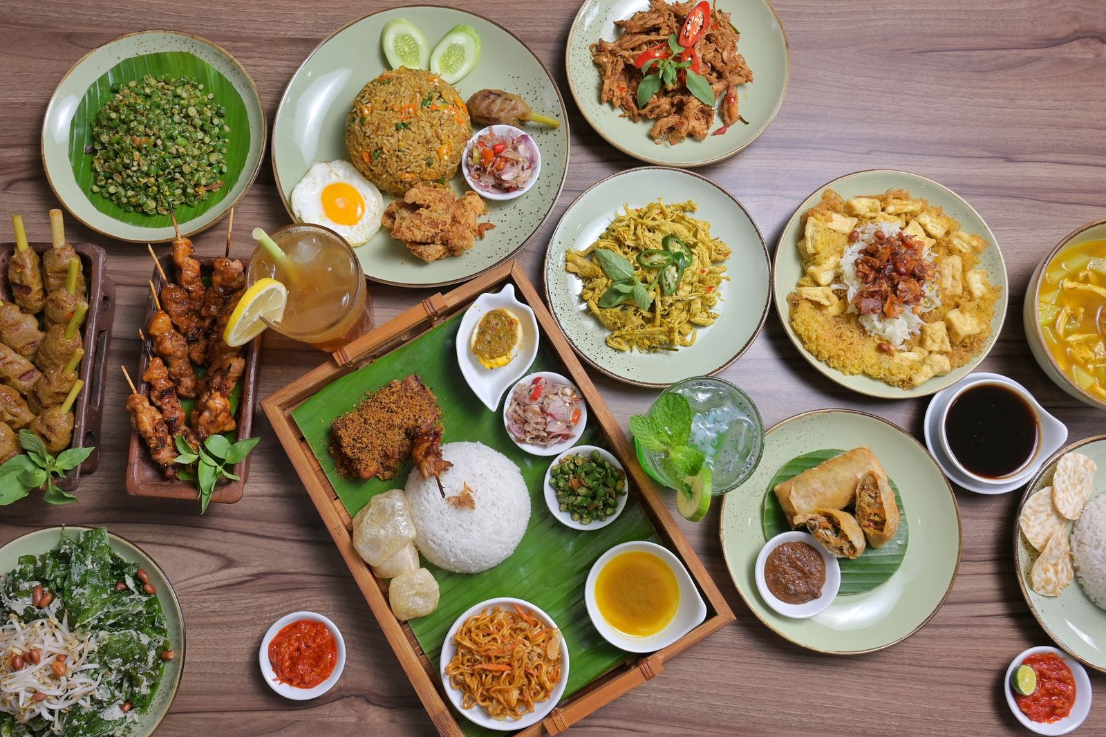 Explore a vibrant spread of traditional Indonesian dishes, beautifully presented on a wooden table.