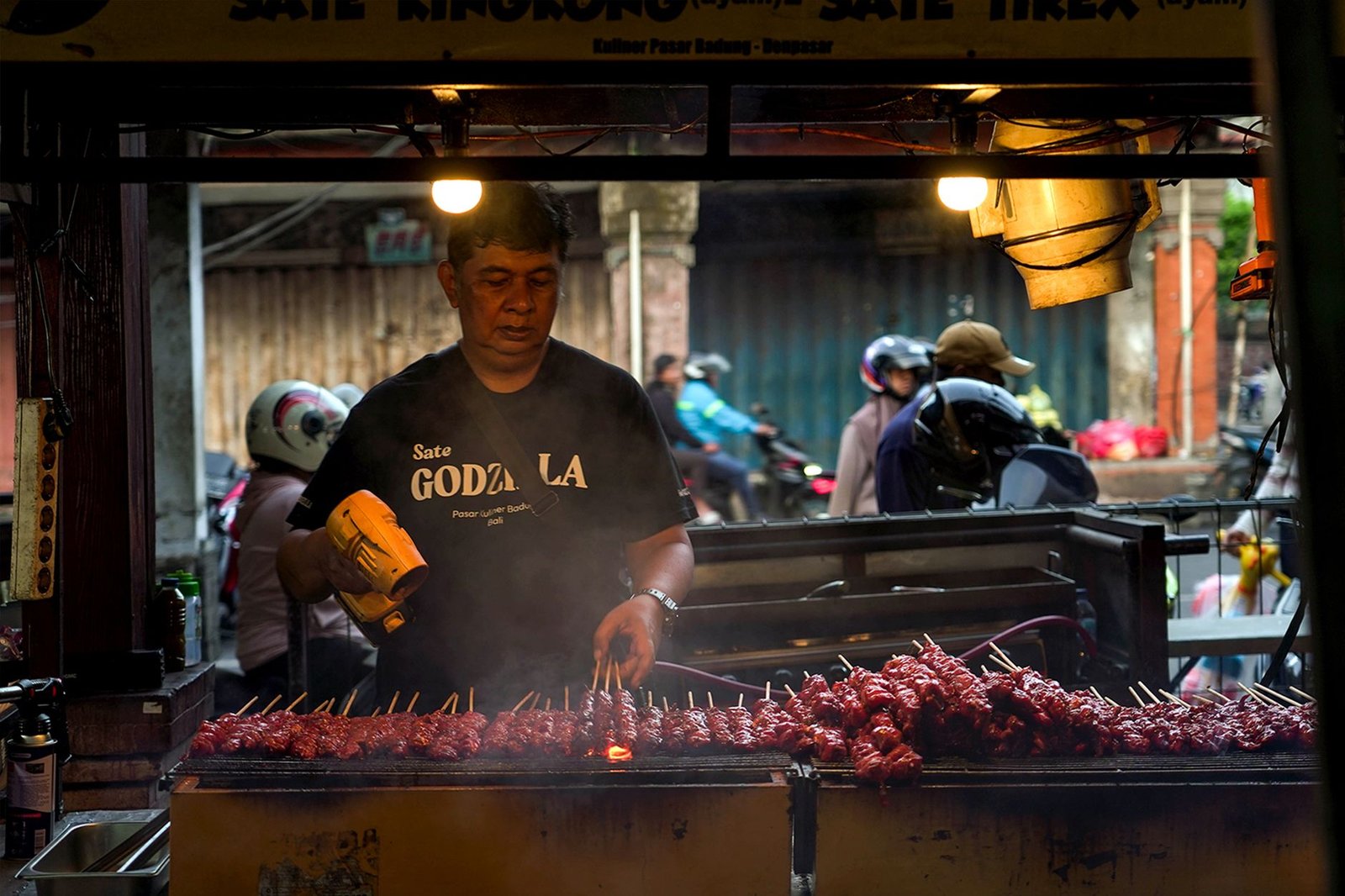 Grilling chicken satay at a street food market in Denpasar, Bali.