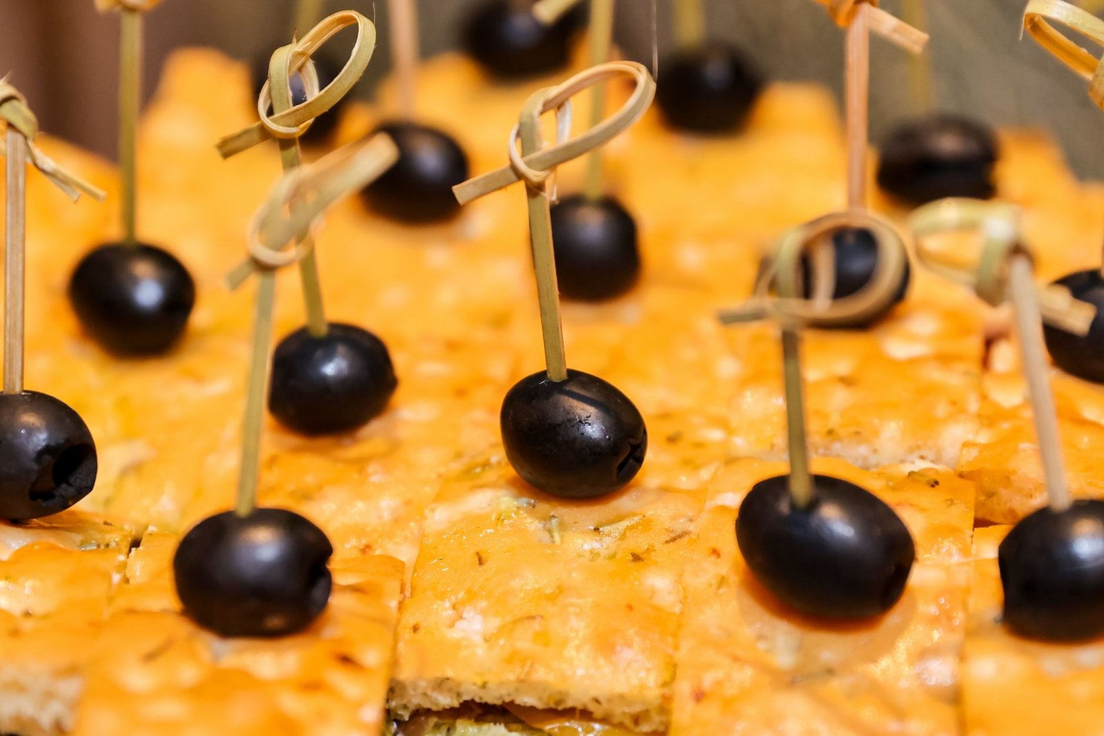 Close-up of delicious black olives on cheese crackers, perfect for party appetizers.