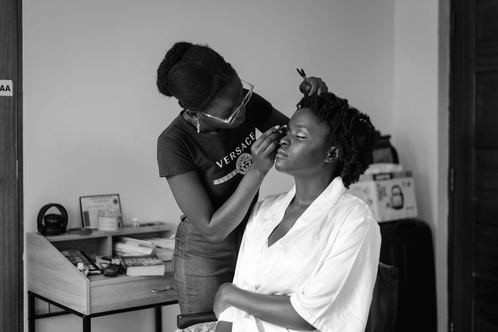 African American woman having makeup applied in monochrome setting.