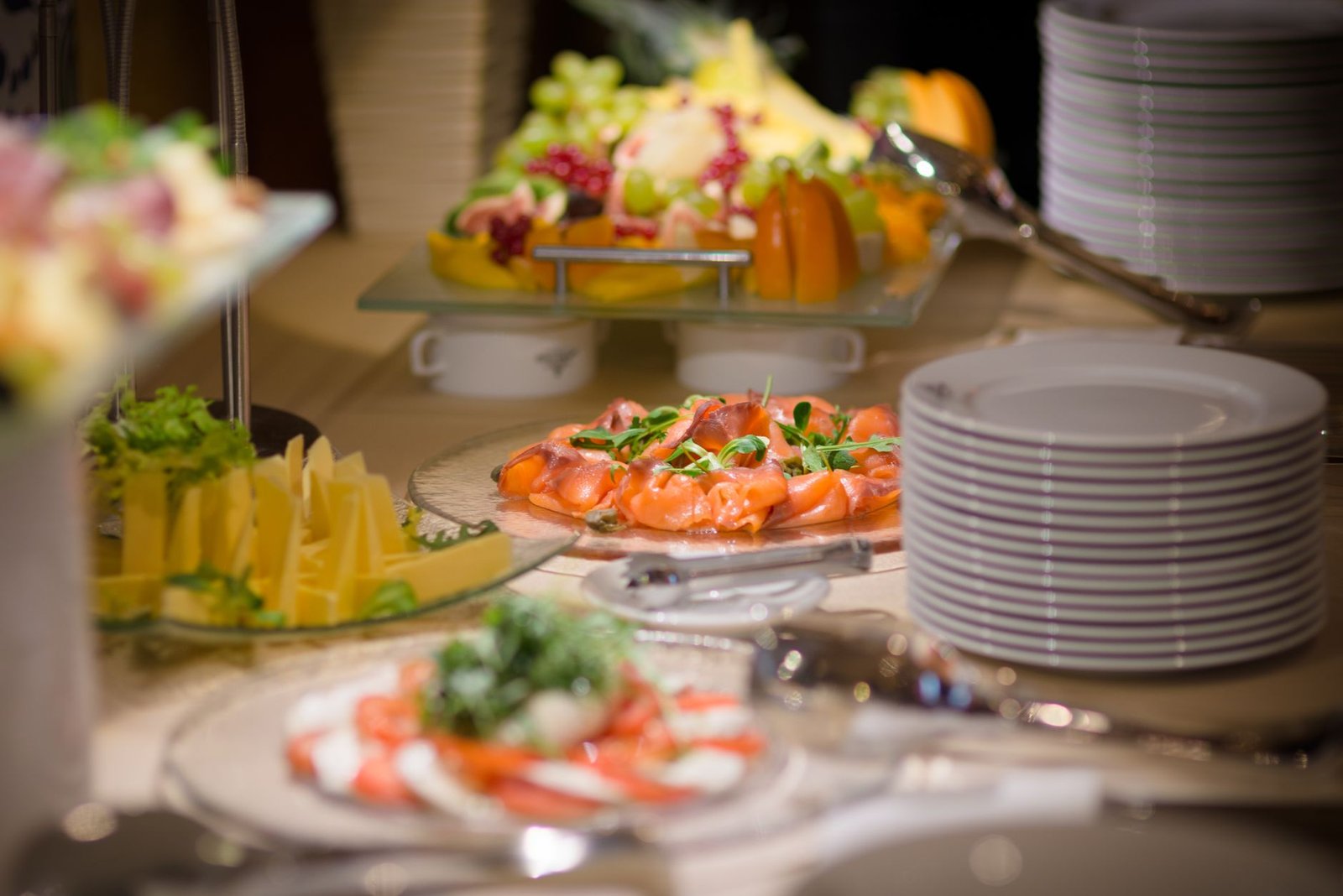 Pengaturan buffet mewah yang menampilkan salmon asap, buah segar, dan piring keju.