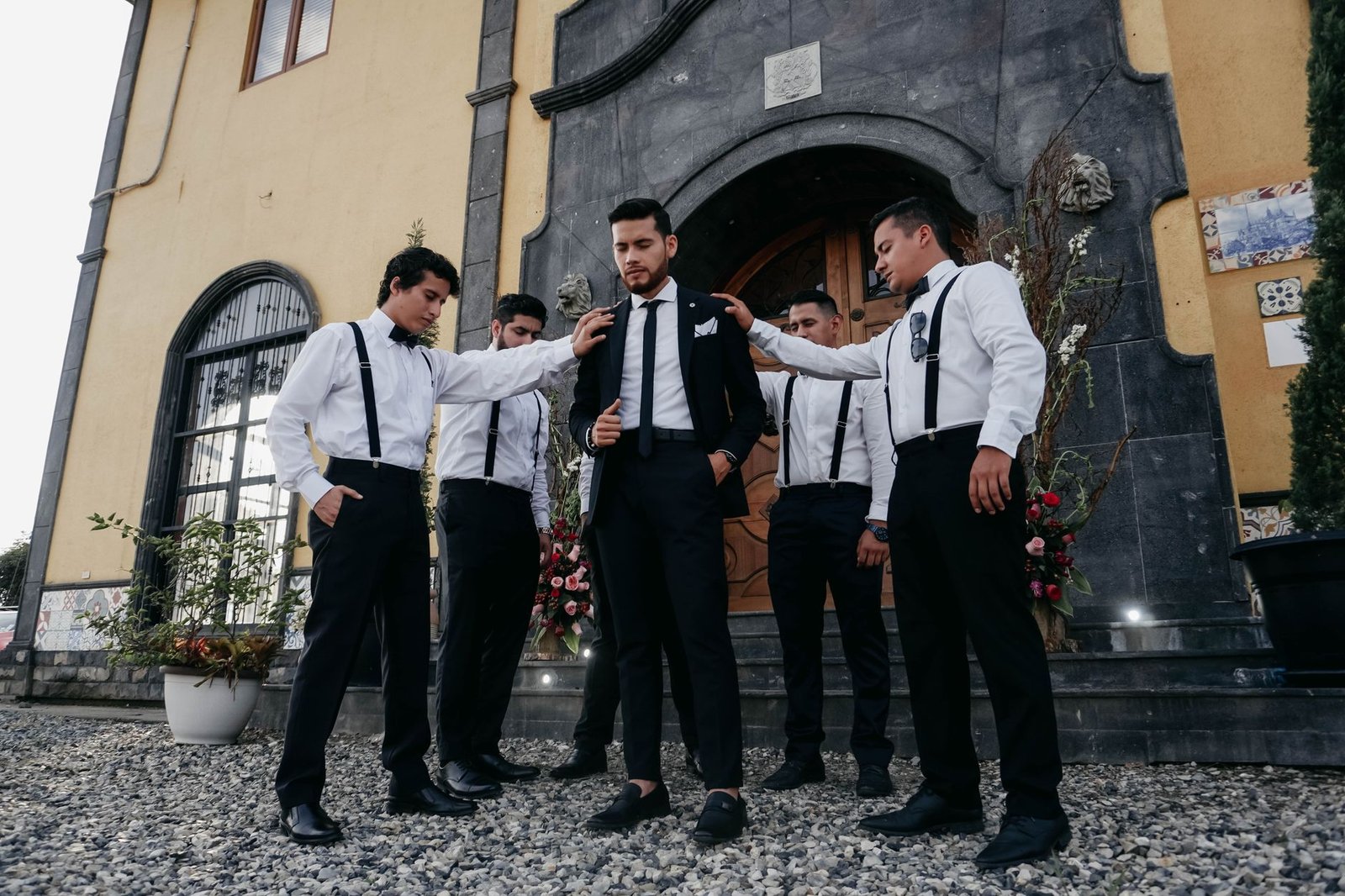 Groom with groomsmen in stylish suits preparing for wedding outdoors in Ecuador.