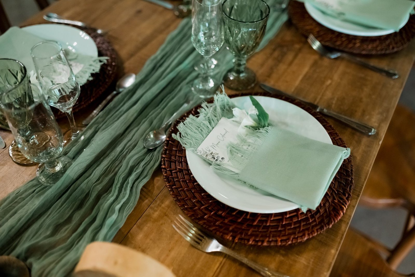 A beautifully arranged table setting with elegant green decorations and dinnerware.