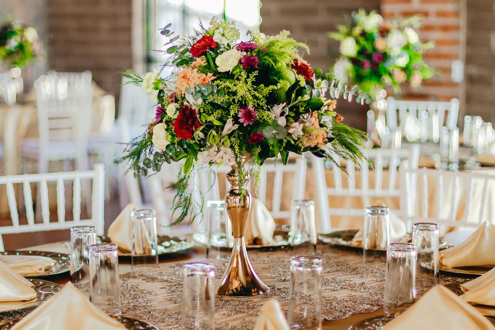 Vibrant floral centerpiece on a formal dining table set for a reception indoors.
