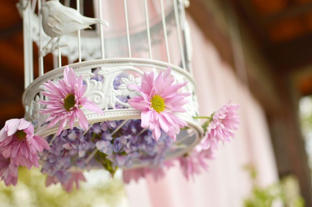 A decorative birdcage adorned with vibrant pink flowers, creating a romantic setting.