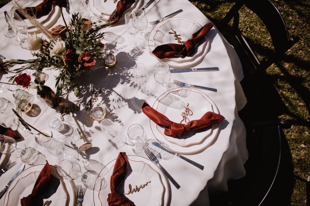 Top-down view of an elegantly set dining table with a floral centerpiece, perfect for outdoor gatherings.