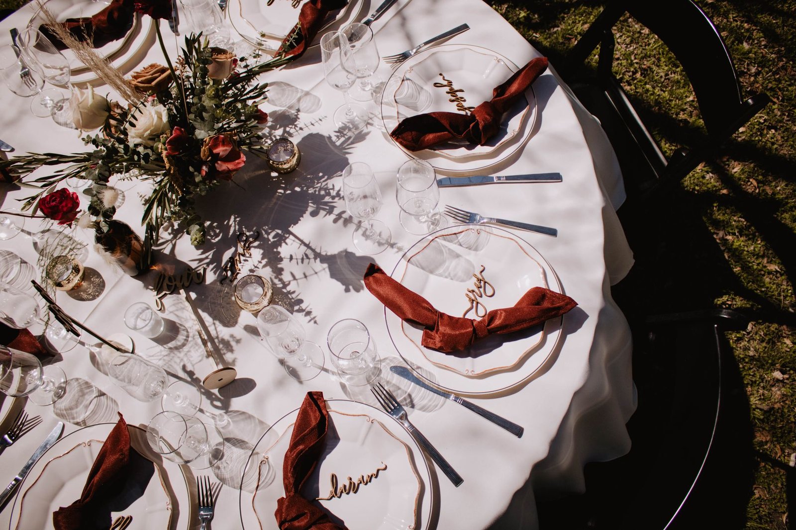 Top-down view of an elegantly set dining table with a floral centerpiece, perfect for outdoor gatherings.
