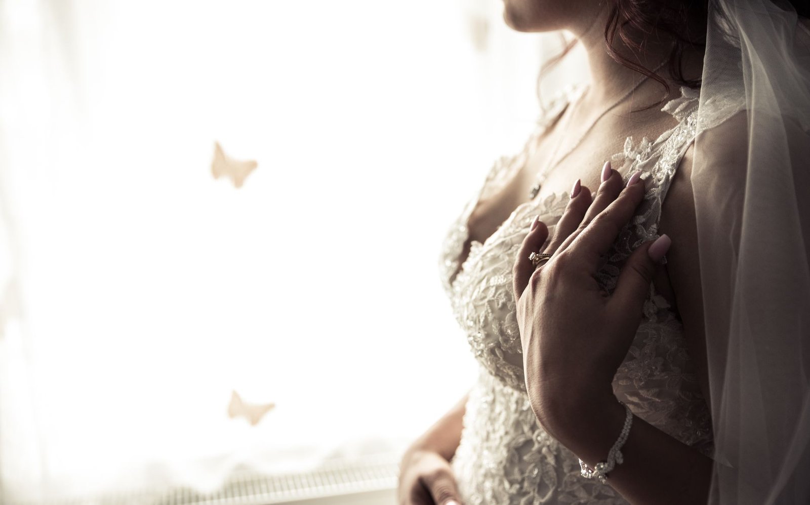 Close-up of a bride wearing a lace dress and ring, showcasing elegance and beauty.